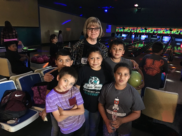 woman posing with students in a bowling alley